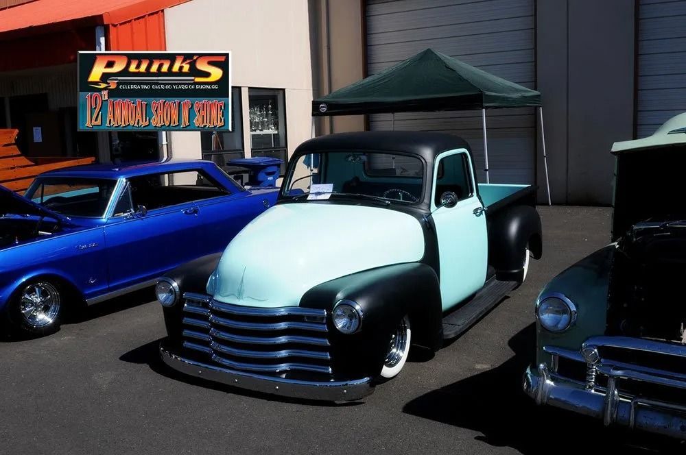 Vintage light blue and black pickup truck at a car show, parked next to other classic cars.