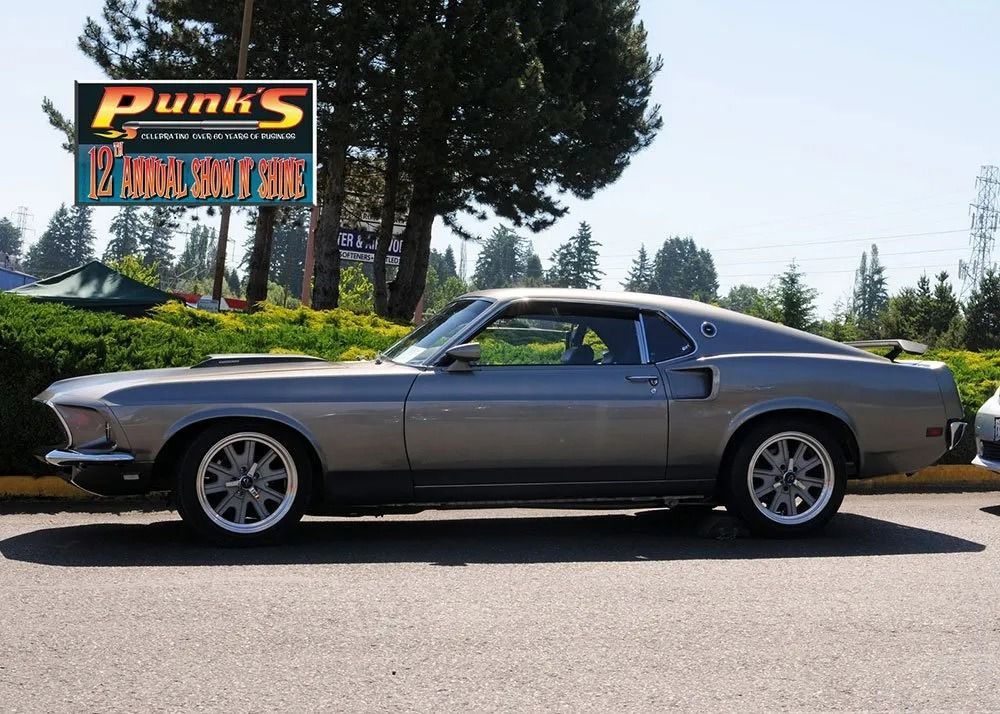 Gray classic Ford Mustang car parked outside a shop.