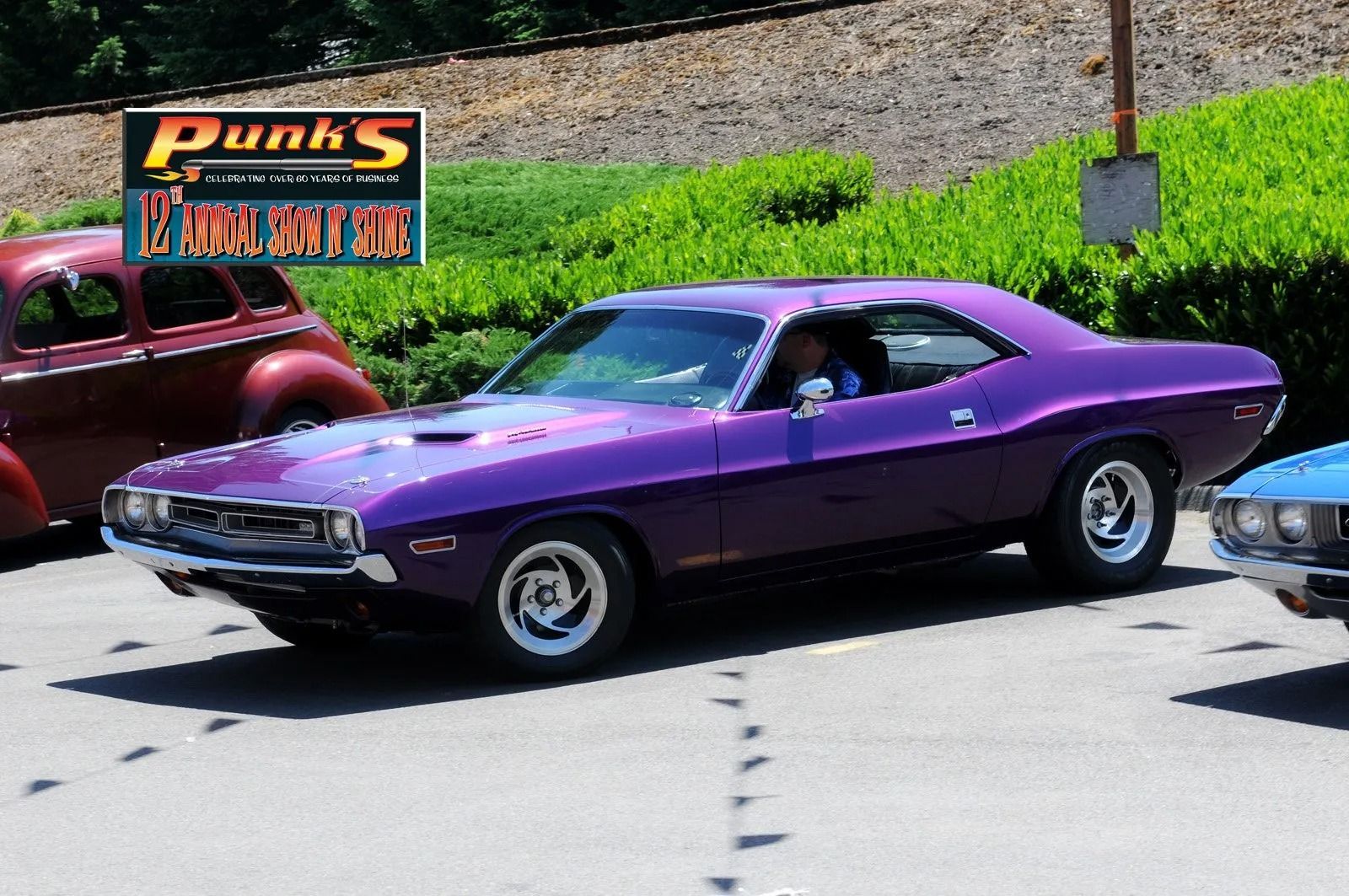 Purple Dodge Challenger car parked, with a restaurant sign in the background.
