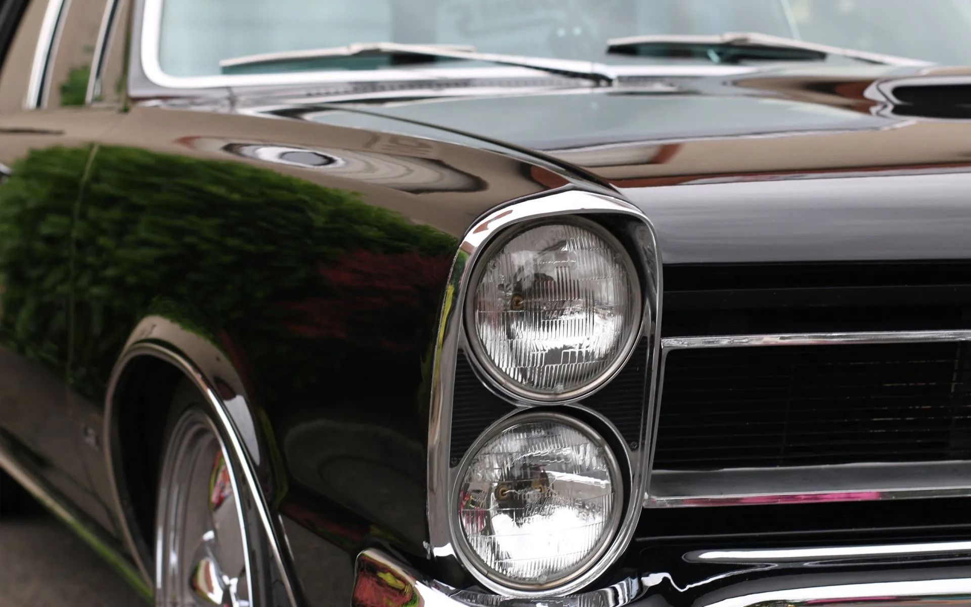 Black classic car, chrome headlight surrounds, close-up.