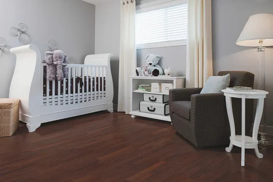 A baby room with a crib , chair , table and lamp.