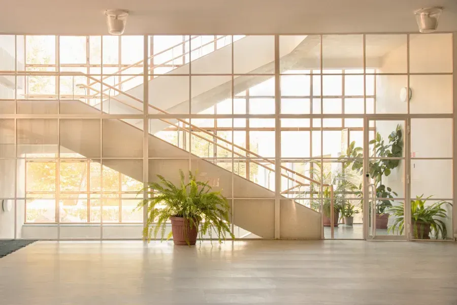 An empty lobby with a staircase and potted plants.