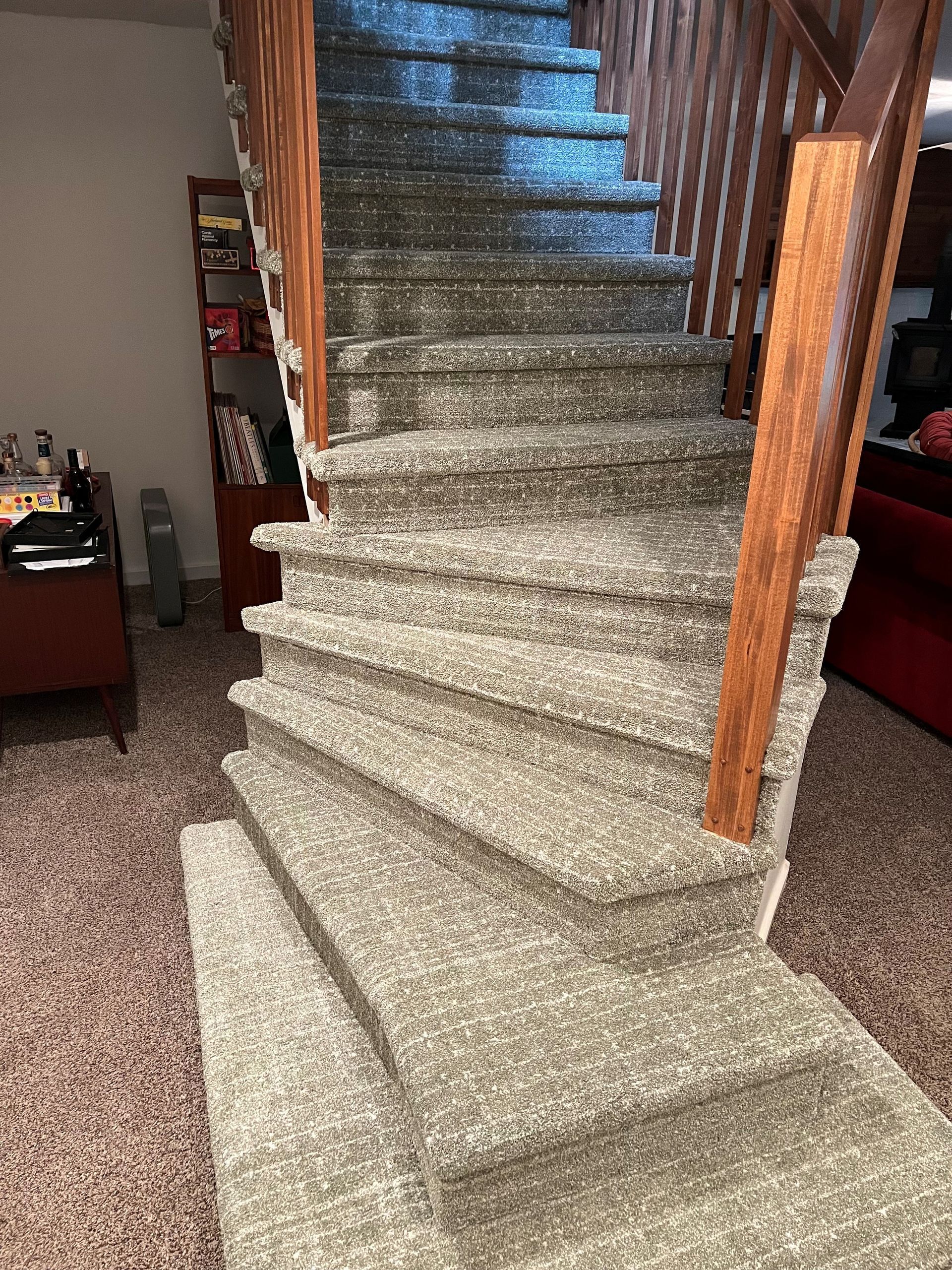 Carpeted staircase with wooden banister and railing in a home setting.