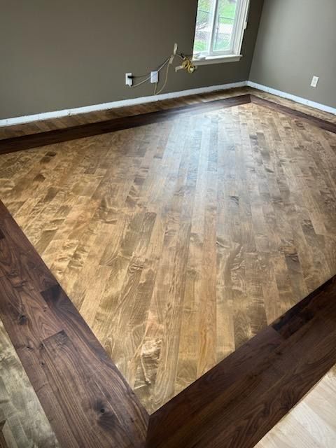 Staircase with white risers, wood treads, and carpeted center sections. A black handrail runs along the right side.
