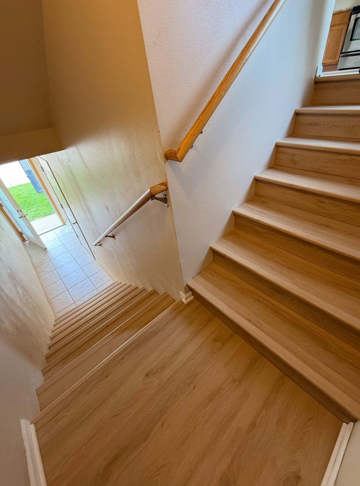 Wooden staircase with a wooden handrail on the right and a landing leading to a door at the end.