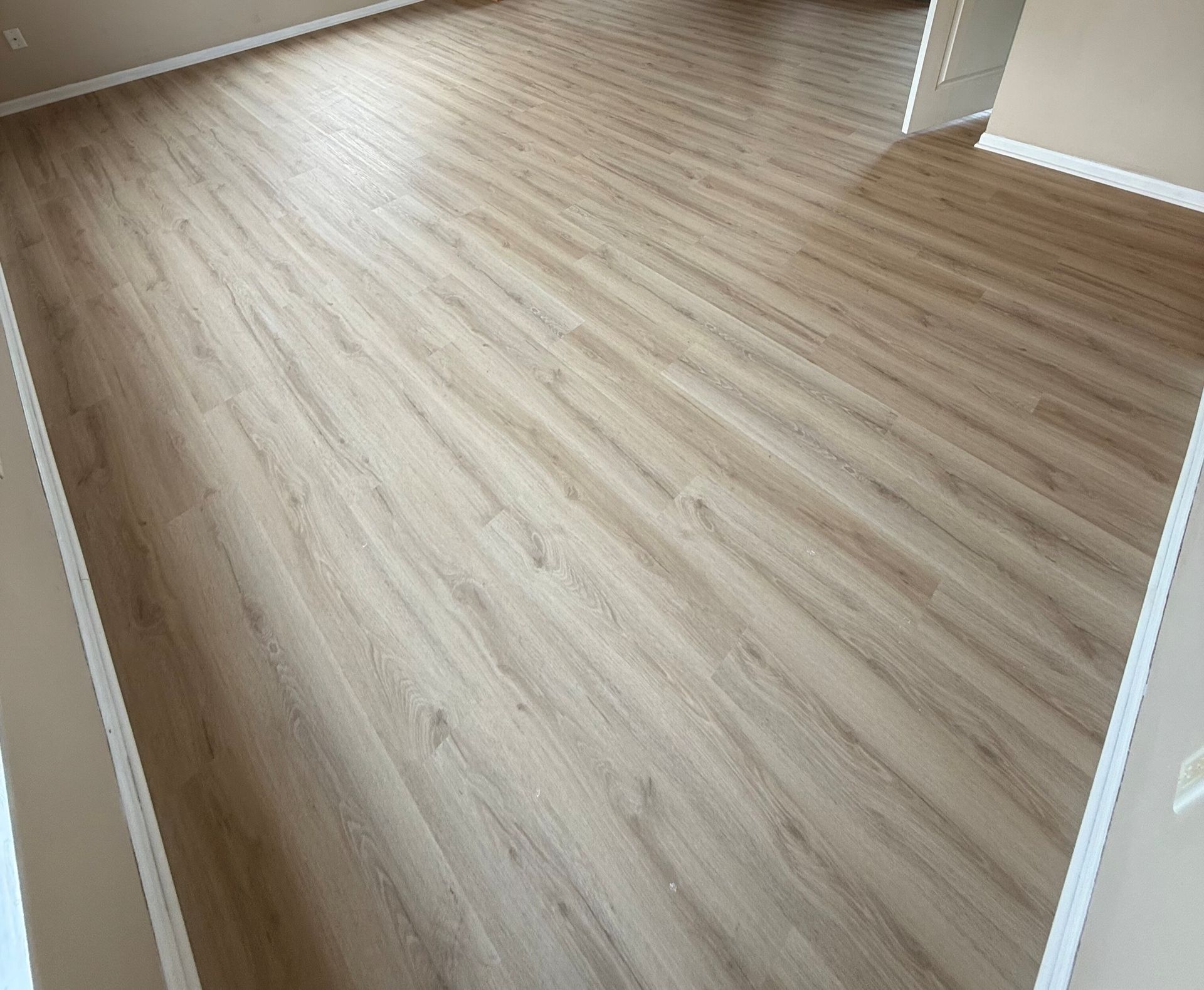 Light brown wood-look flooring in a room, with walls visible along the sides.