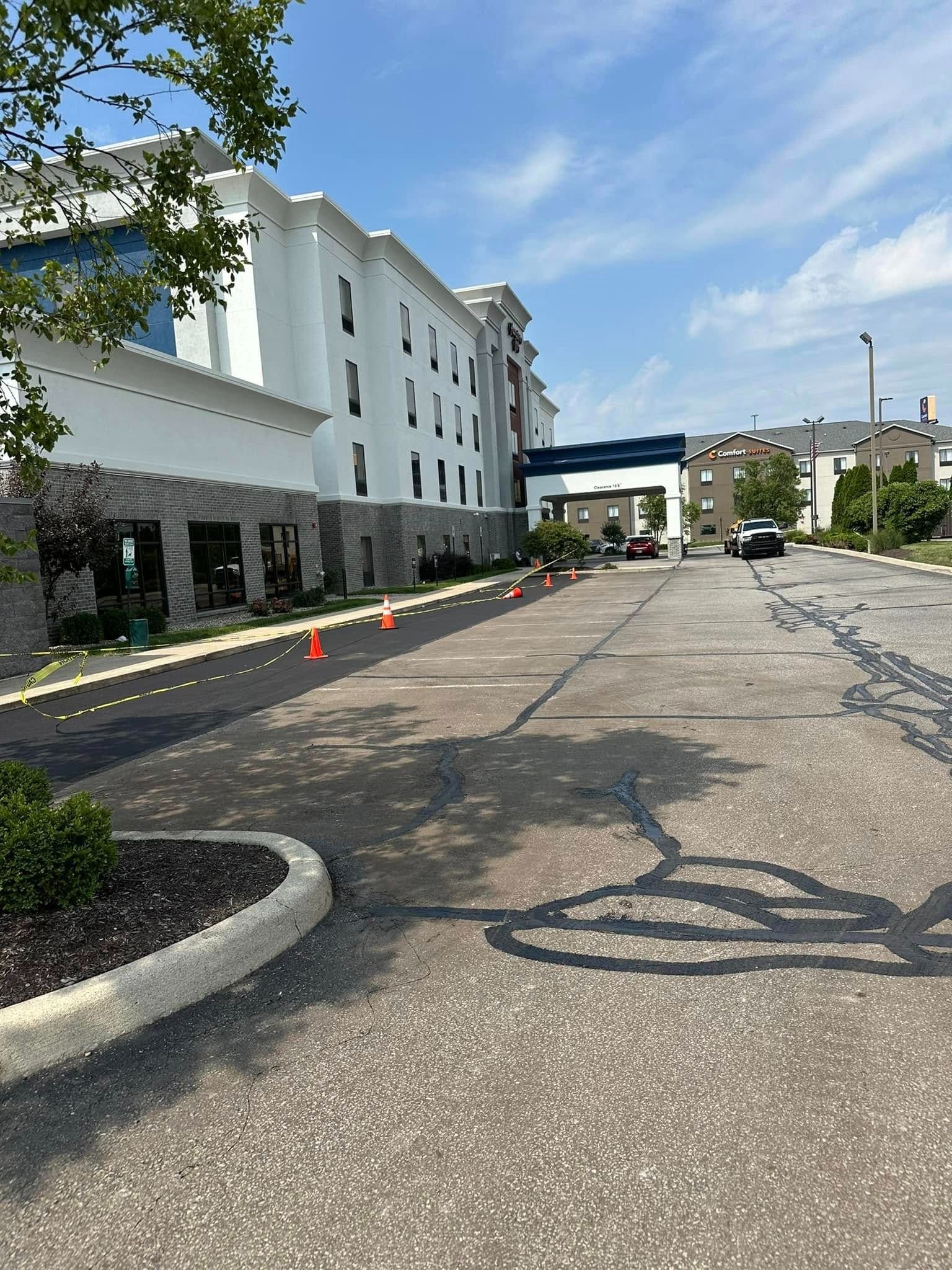 Hotel exterior with driveway and orange traffic cones under a blue sky.