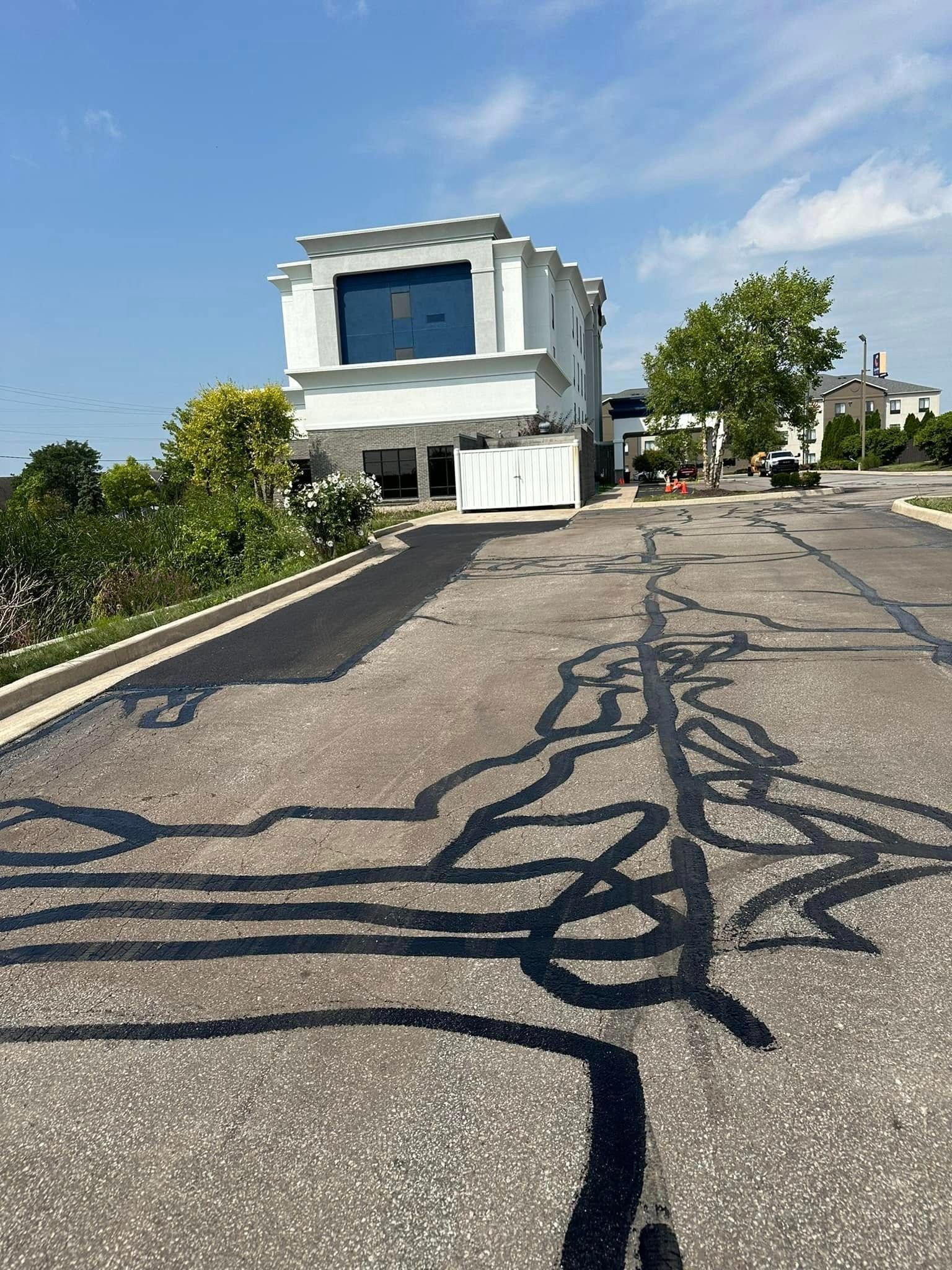 Two-story white building with large blue window and asphalt road with black crack sealant in foreground.