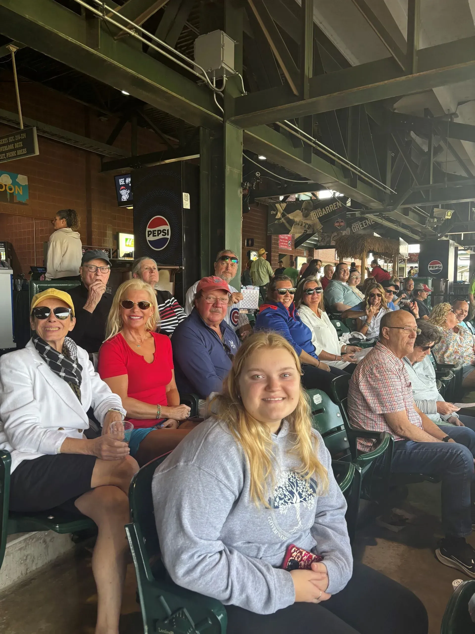 A group of people sitting in stadium seating, smiling at a baseball game.