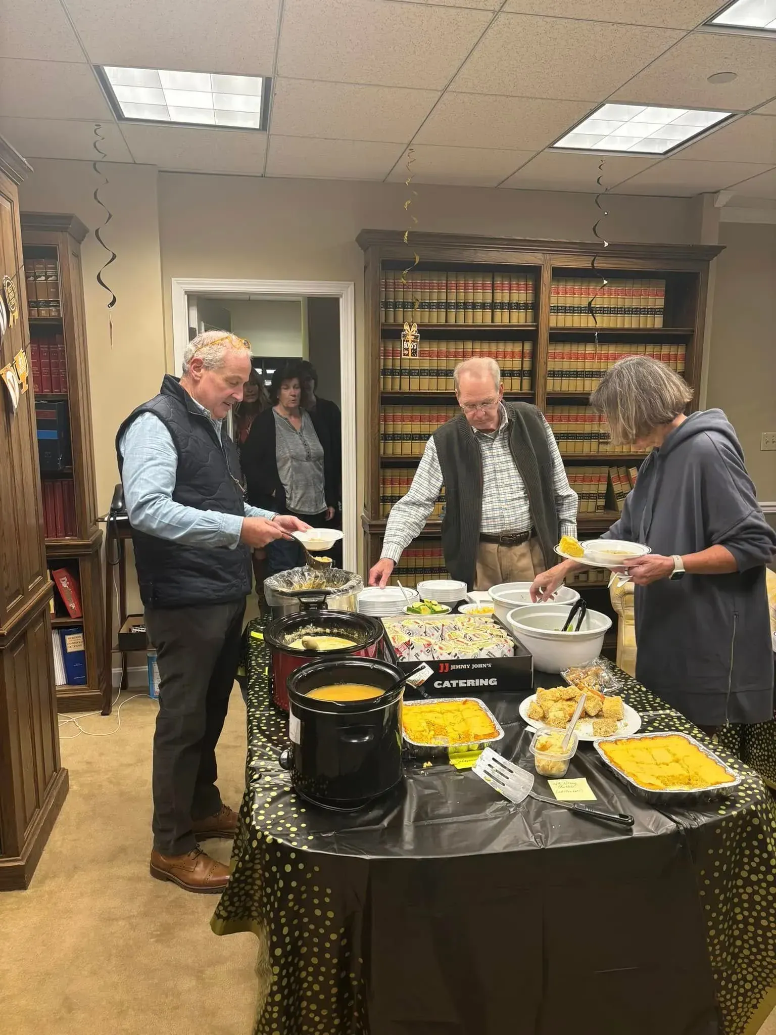 People at a buffet table, choosing food in an office.