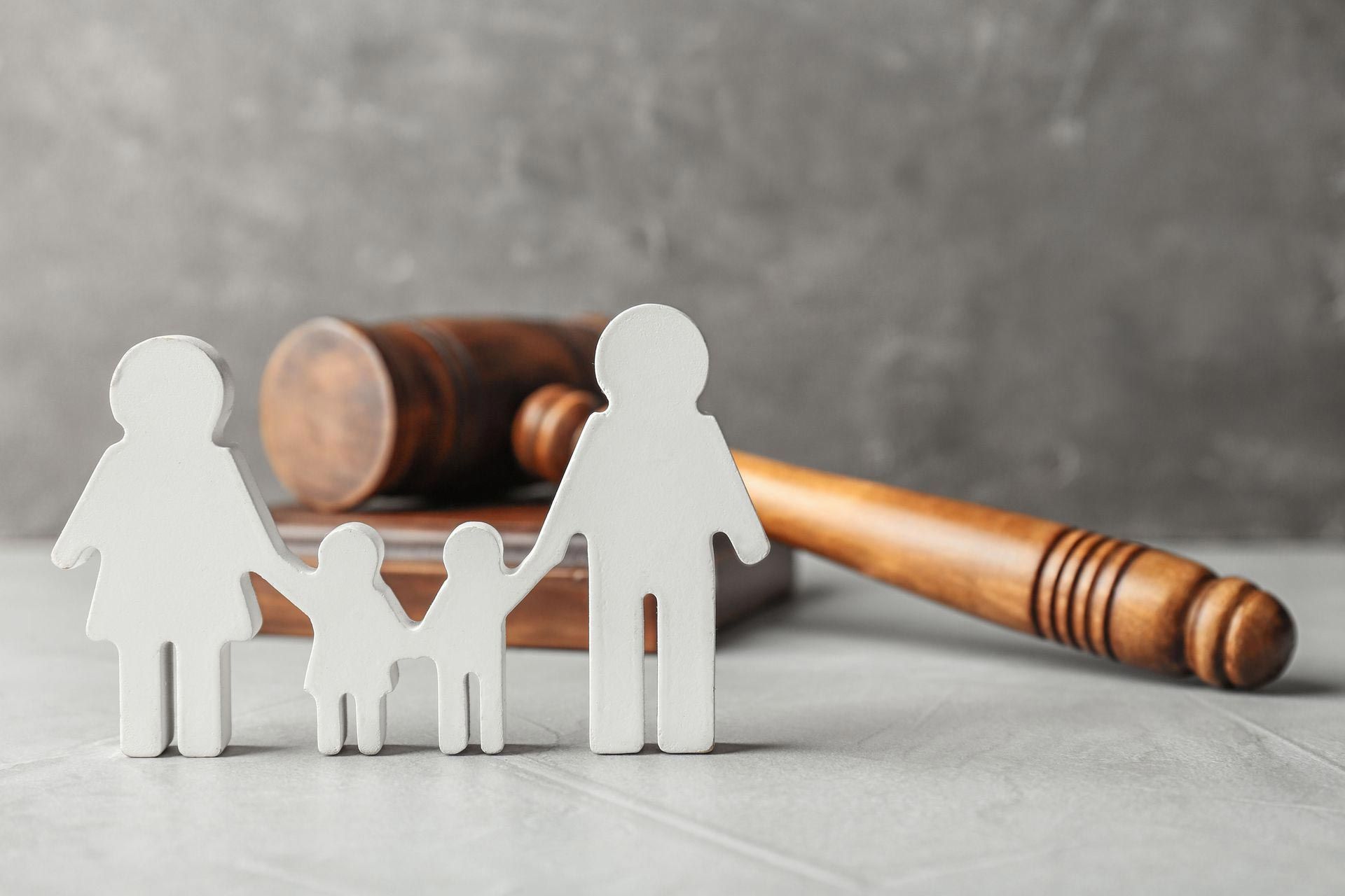 Wooden family figures and a gavel on a white surface, representing family law.