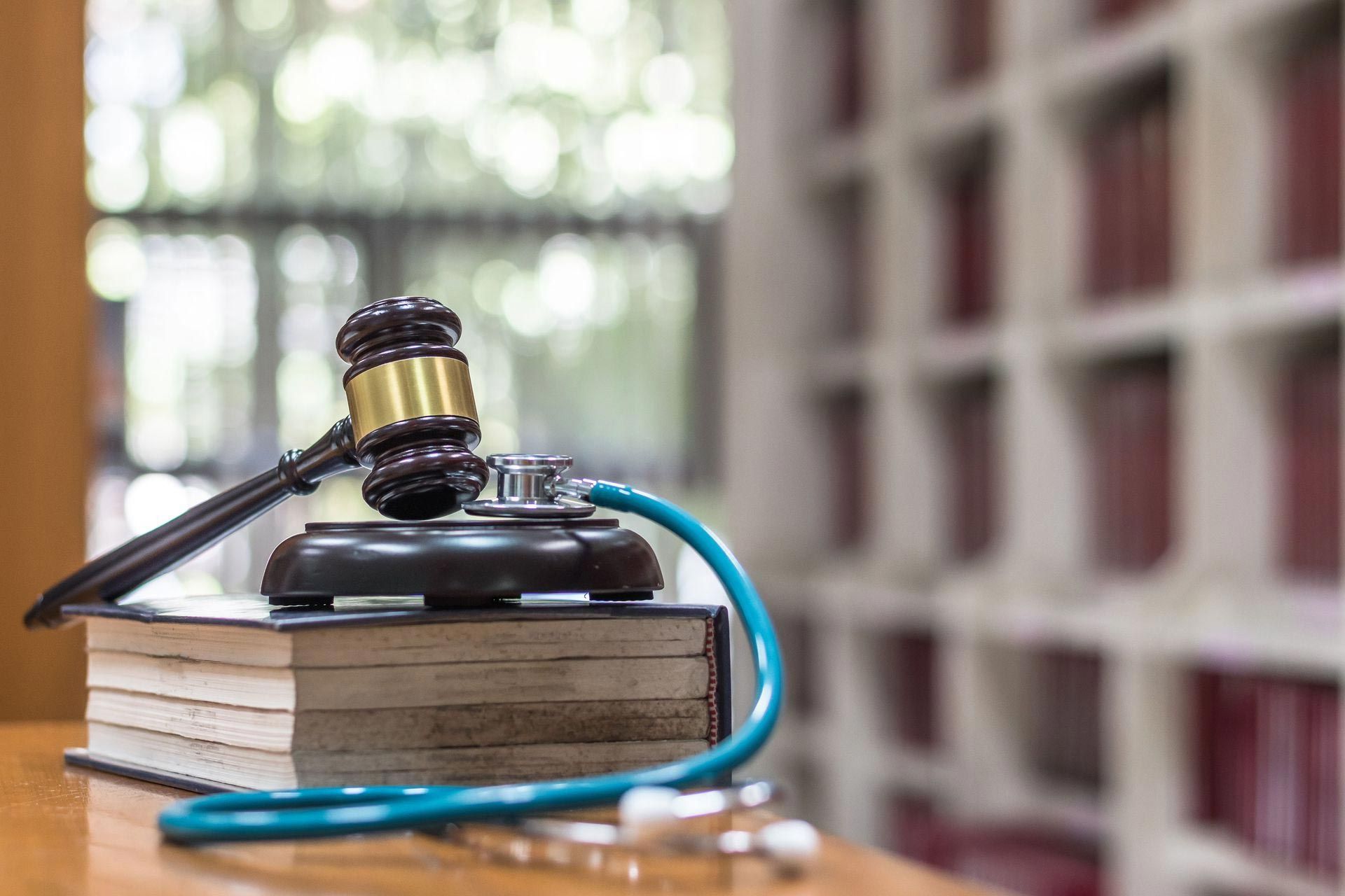 Gavel and stethoscope on books, suggesting legal and medical combination.
