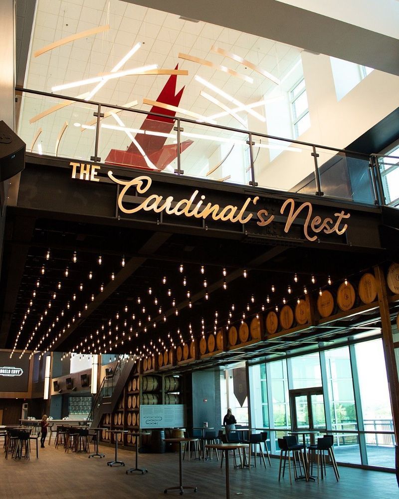 Interior of The Cardinal's Nest with string lights, barrel decor, and large windows.
