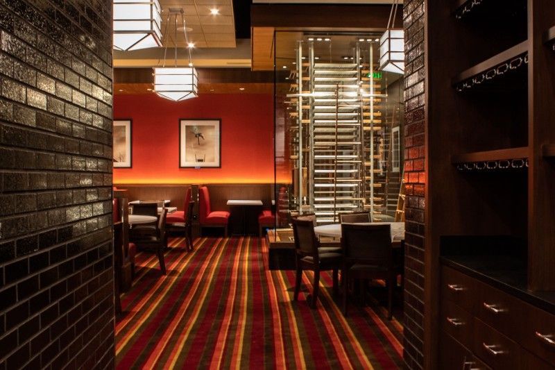 A restaurant with a red striped carpet and tables and chairs.