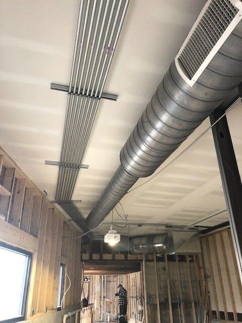 A man is working on the ceiling of a building under construction