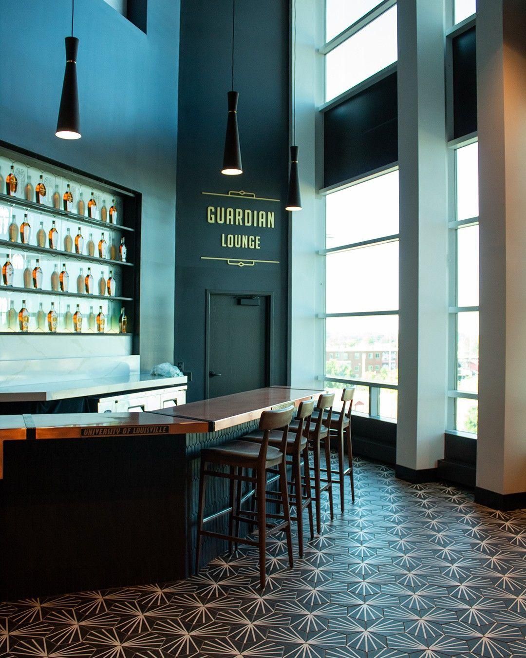Modern bar interior with pendant lights, tall stools, and patterned carpet in blue tones