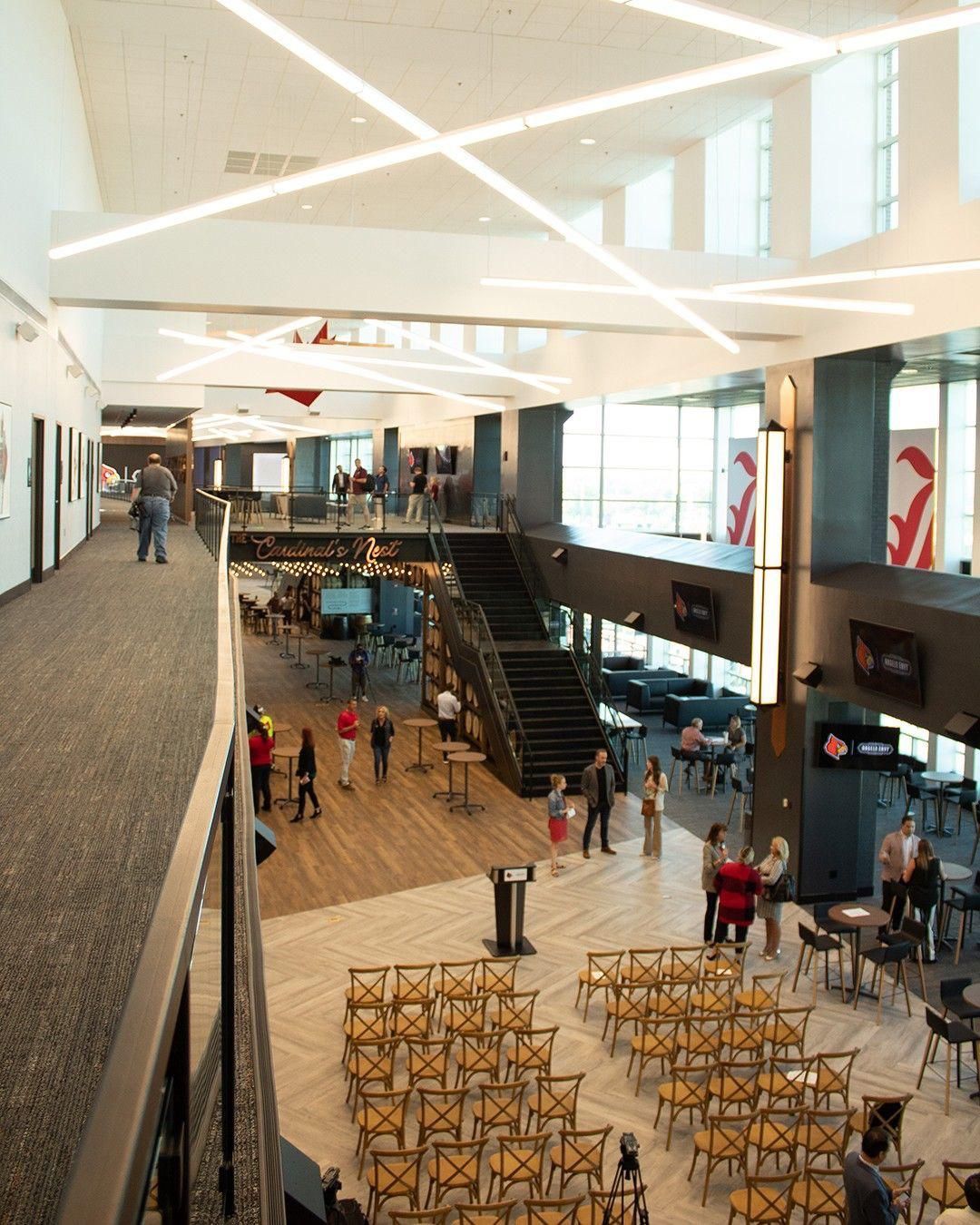 Bright modern lobby with escalators, seating, and people walking under a geometric ceiling