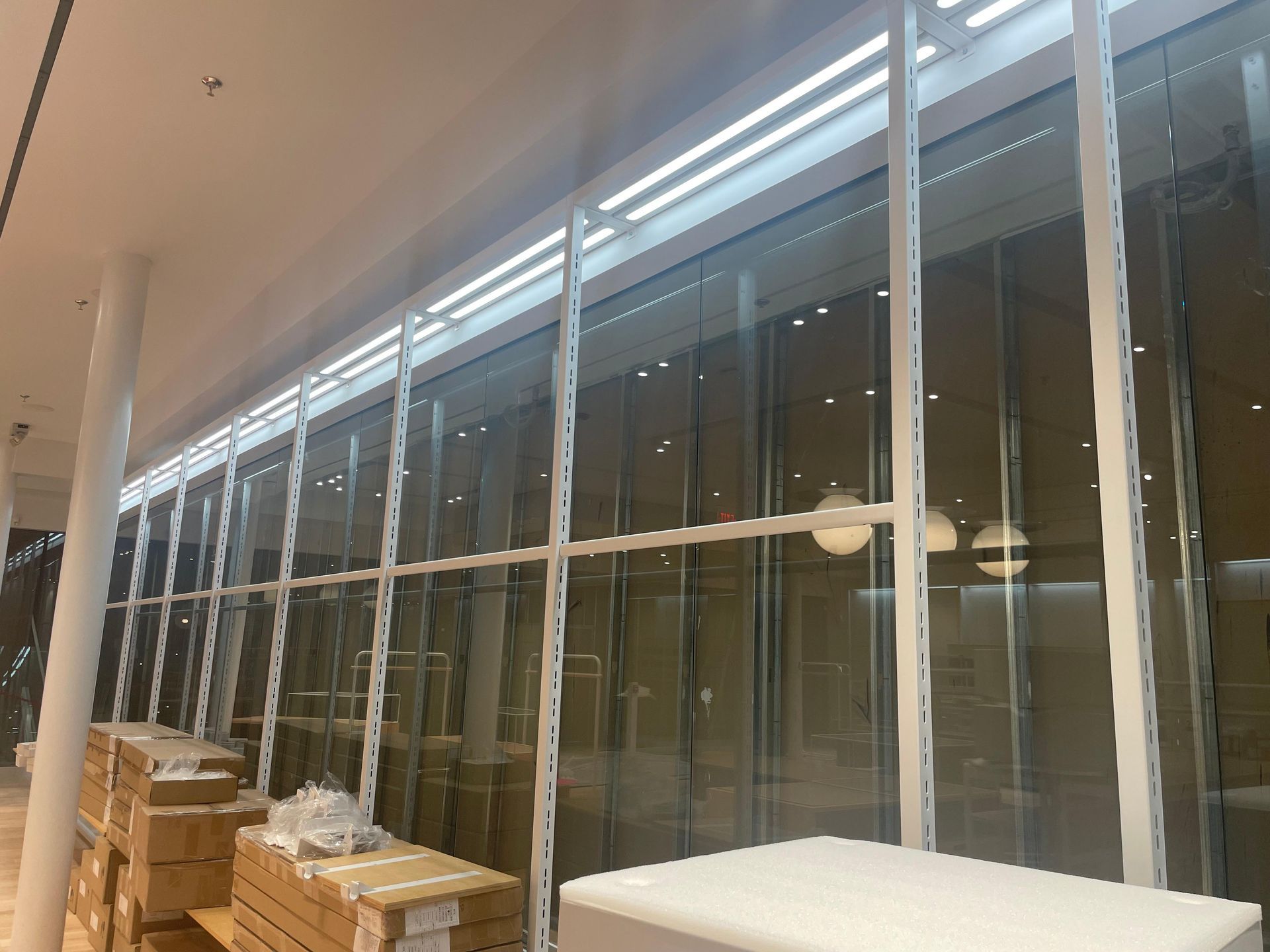 Long glass wall in a modern building interior with stacked boxes and a covered table.