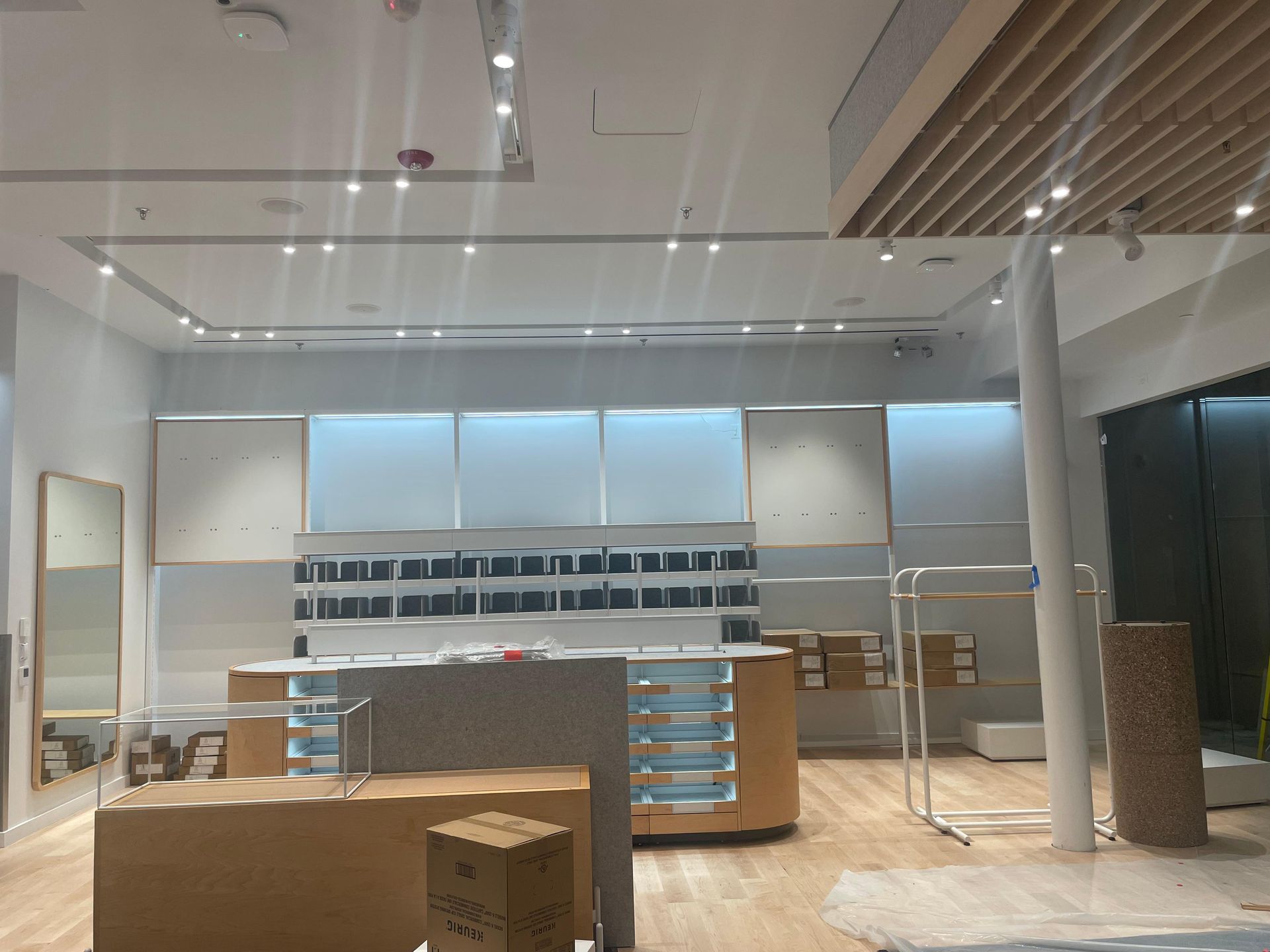 Empty modern retail store interior with white shelves, wood counters, and bright ceiling lights
