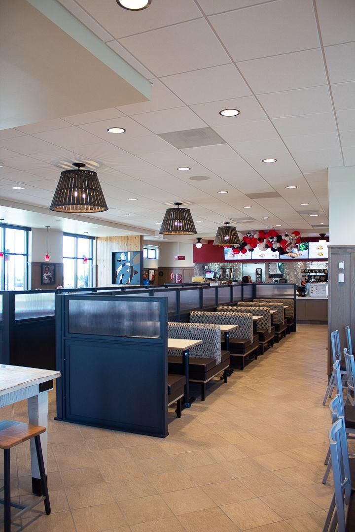 Empty diner seating area with blue booths, tables, and pendant lights under a white ceiling