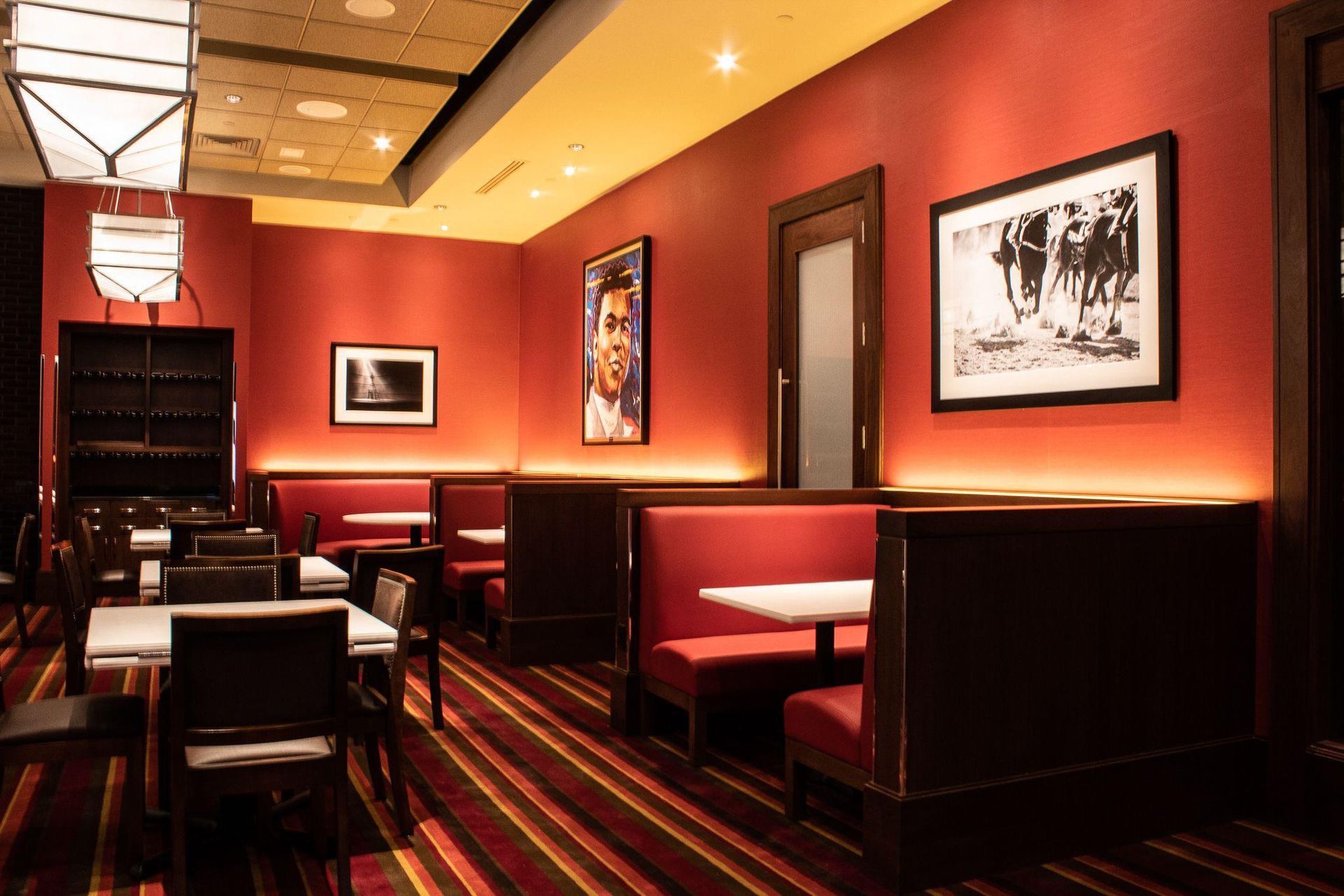 Dimly lit red restaurant booth seating with framed black-and-white photos on the walls