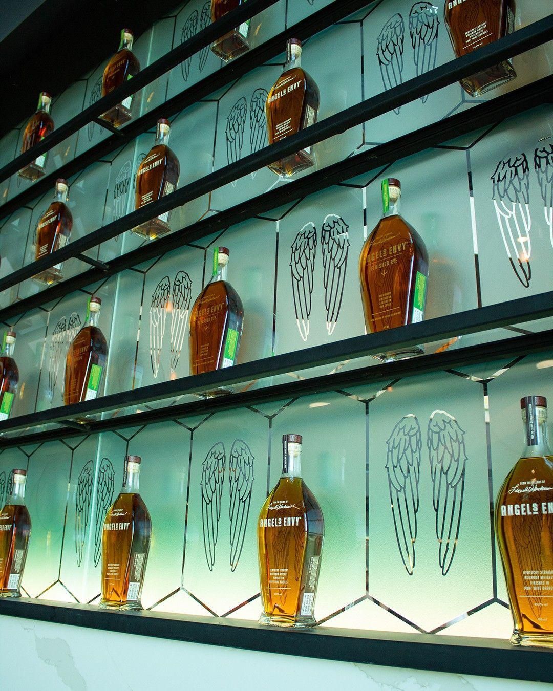 Rows of amber liquor bottles on lit glass shelves in a bar display