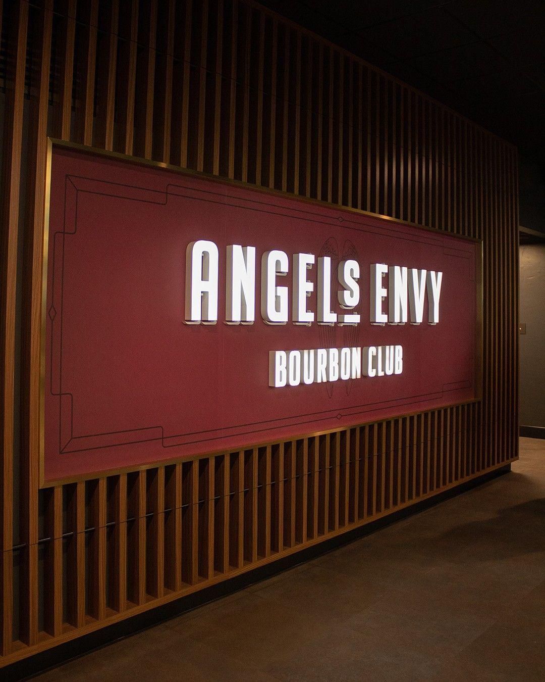Sign for Angels Envy Bourbon Club on a dark wood wall
