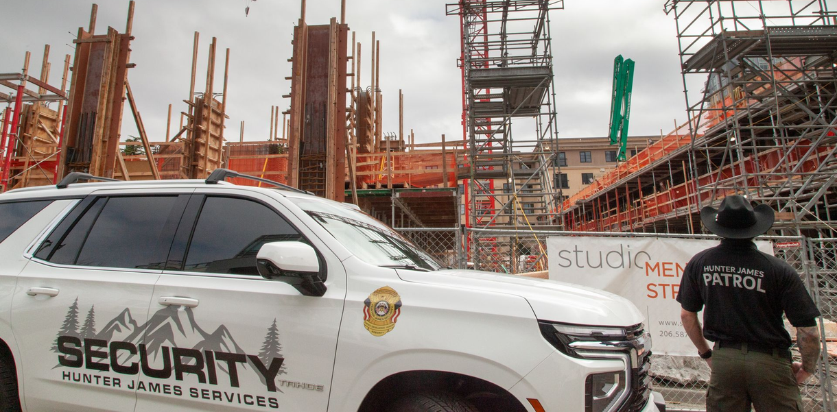 A white security vehicle parked at a construction site with a guard in uniform standing nearby.