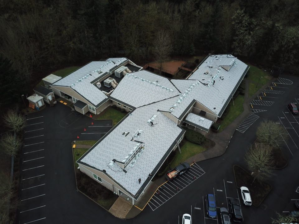 An aerial view of a large building with a parking lot in front of it.
