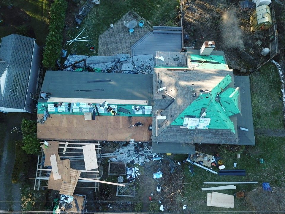 An aerial view of a house under construction with a roof being installed.