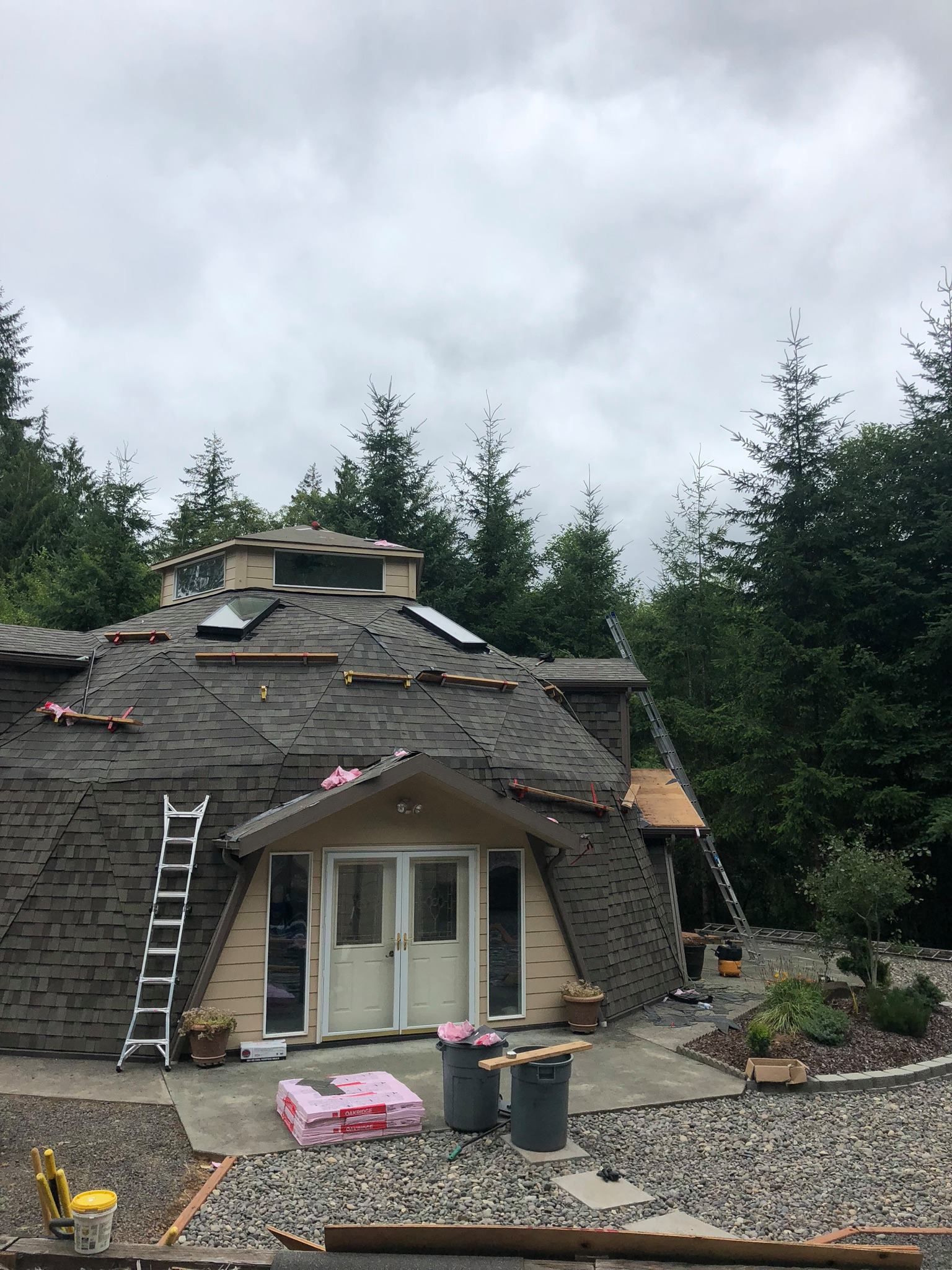 A dome shaped house is being built in the middle of a forest.