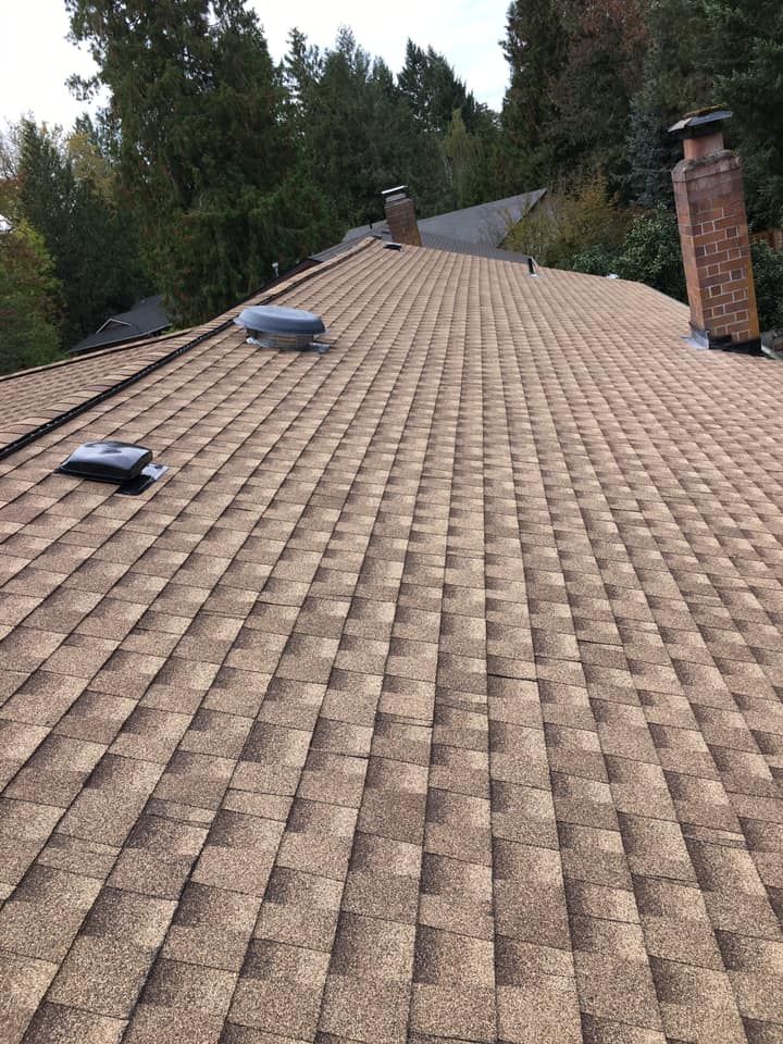A close up of a roof with a chimney and skylights.