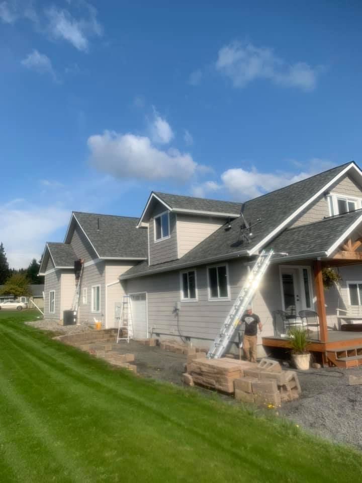 A man is standing in front of a house with a ladder attached to it.
