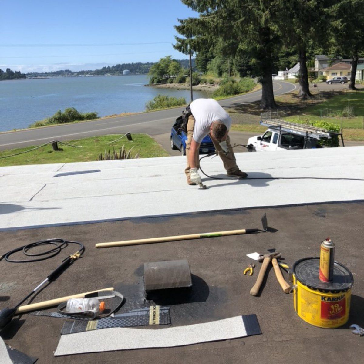 A man is working on a roof near a body of water.