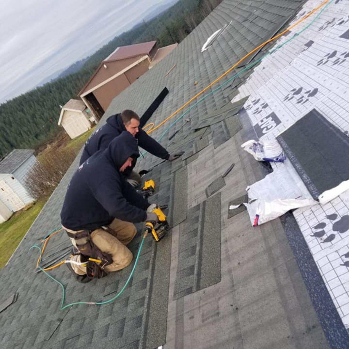Two men are working on the roof of a house.