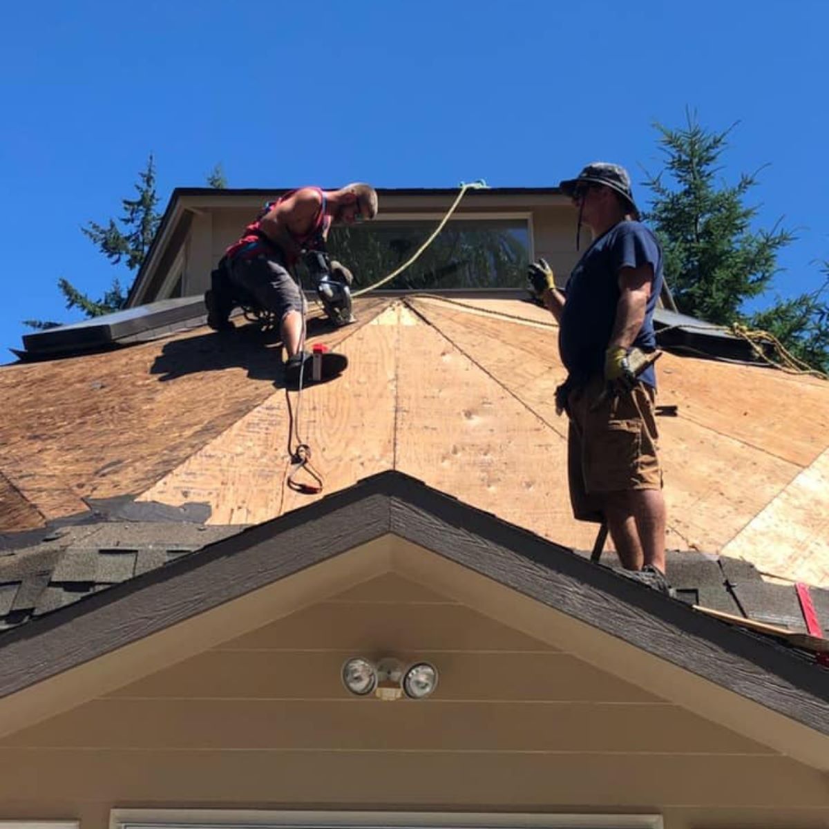 Two men are working on the roof of a house.