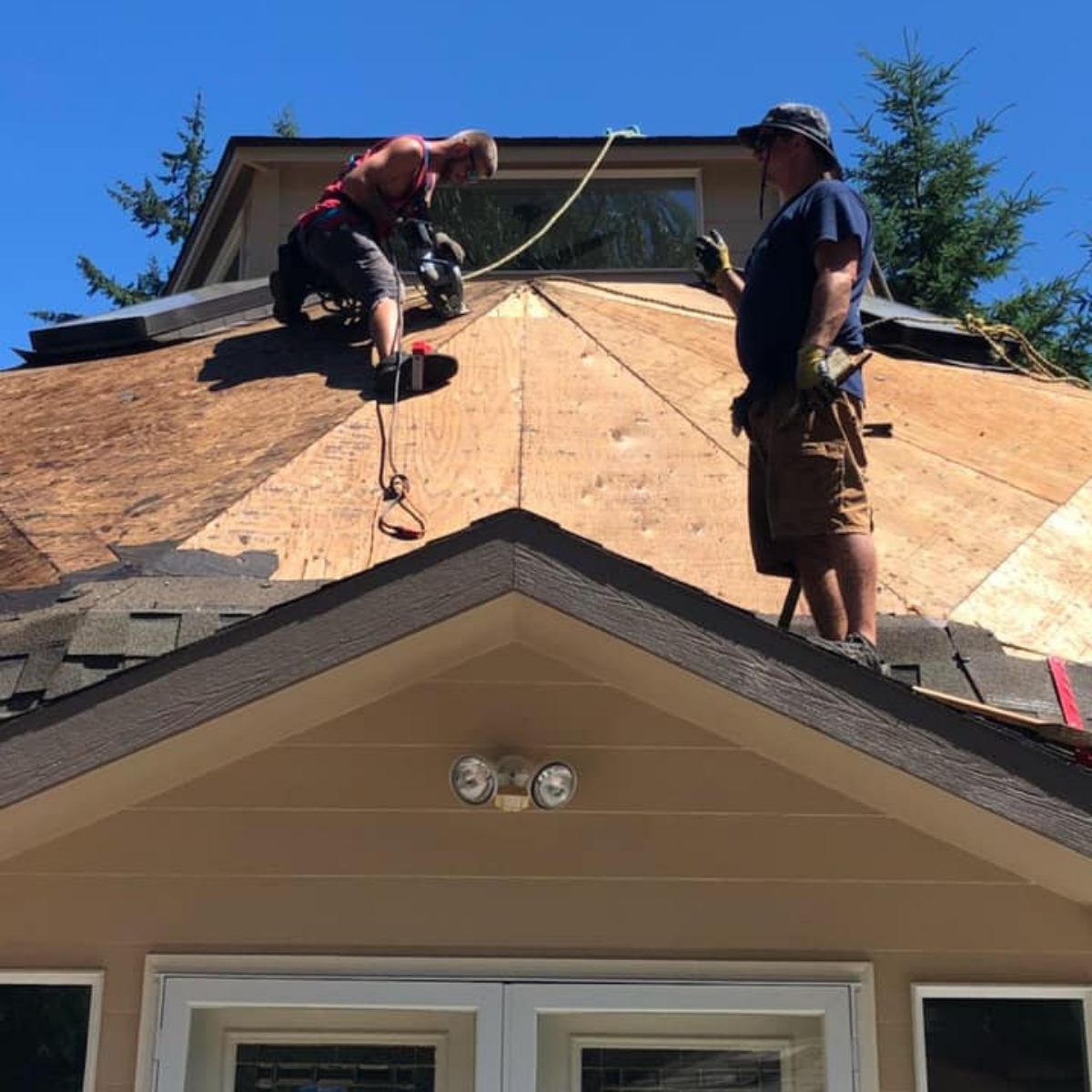 Two men are working on the roof of a house.