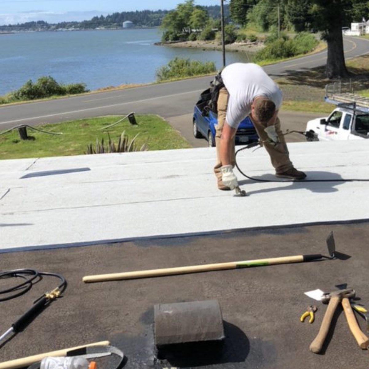 A man is working on a roof overlooking a body of water.
