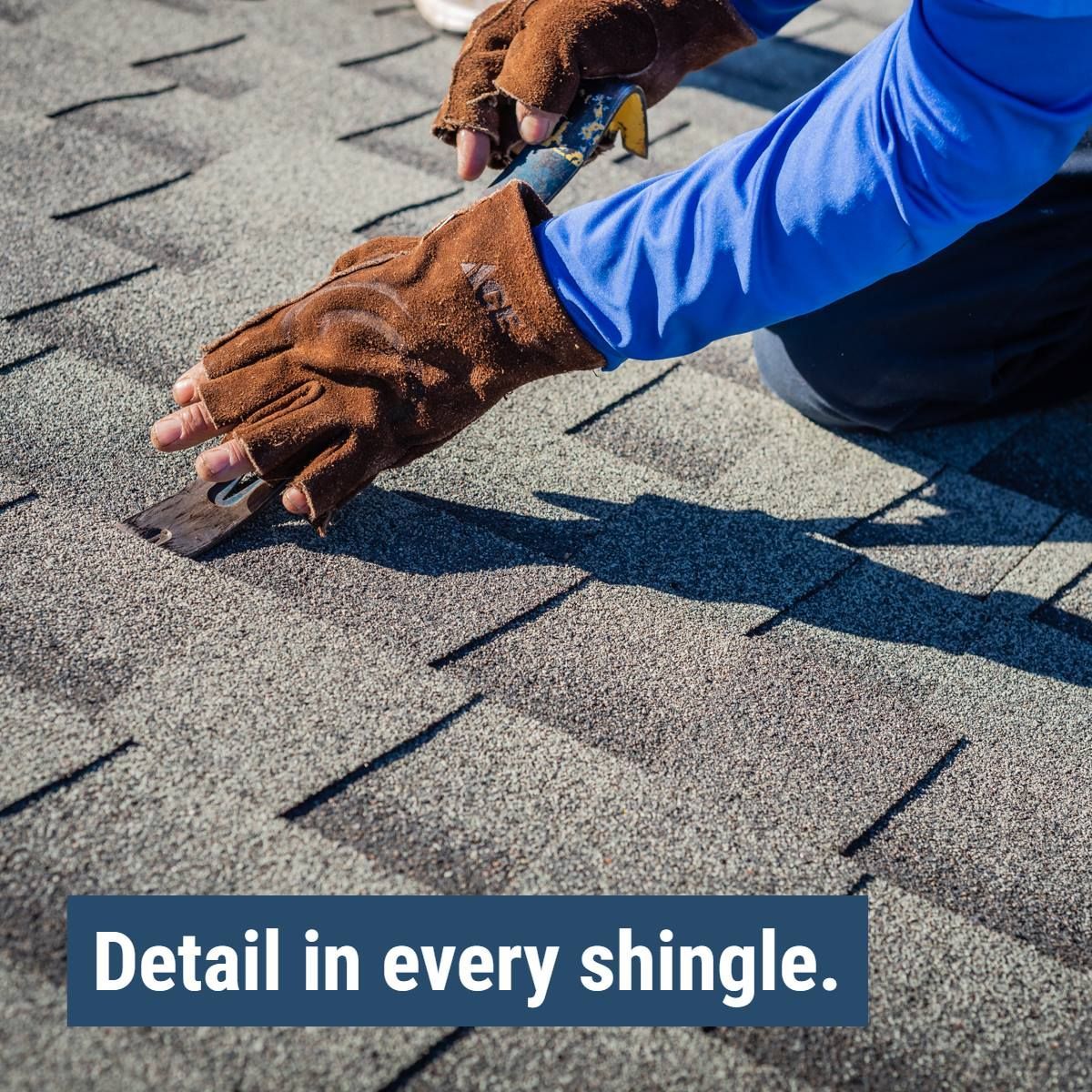 A person wearing gloves is working on a shingle roof.