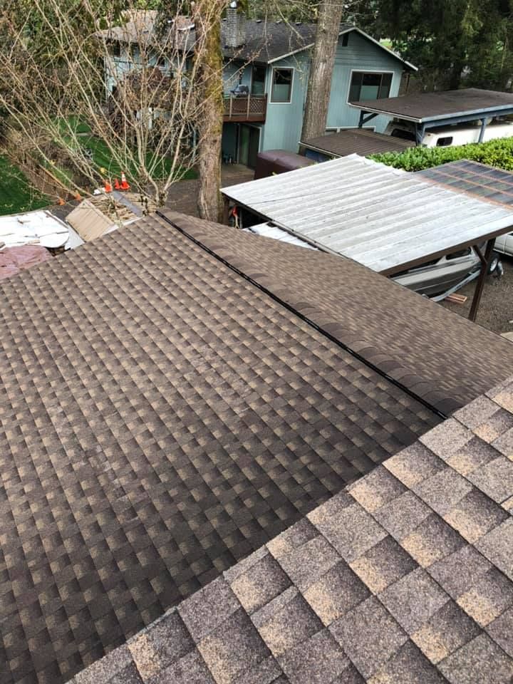 A roof with a lot of shingles on it and a carport in the background.