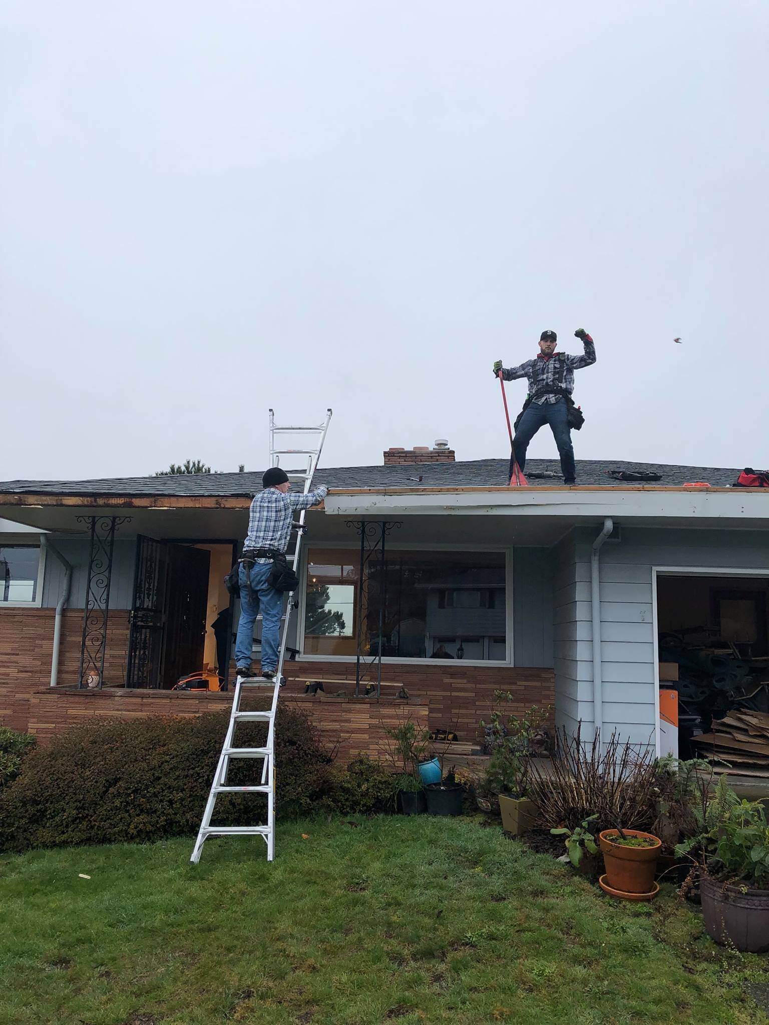 Two men are working on the roof of a house.