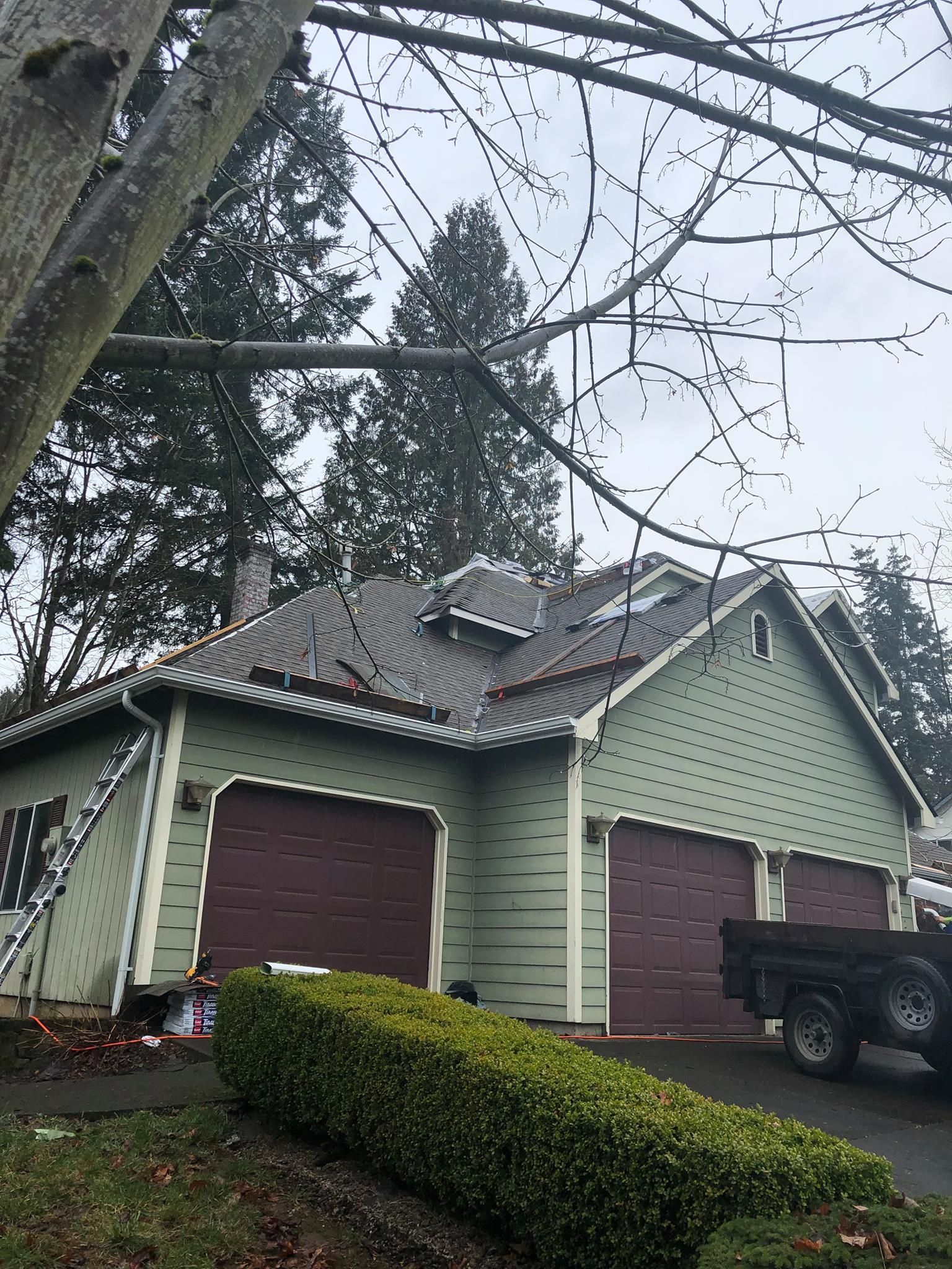 A green house with two garage doors and a truck parked in front of it.