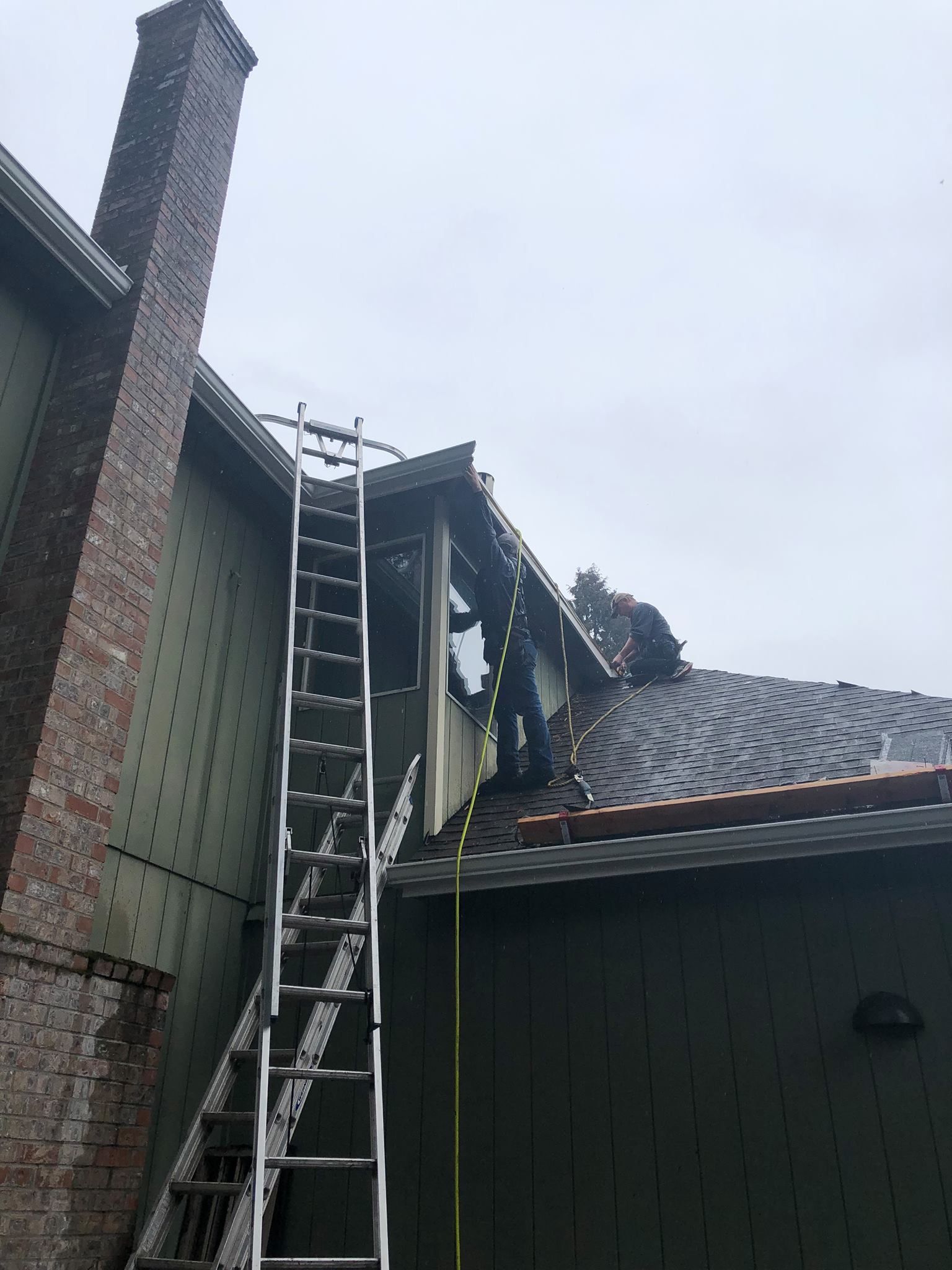 A man is working on the roof of a house with a ladder.