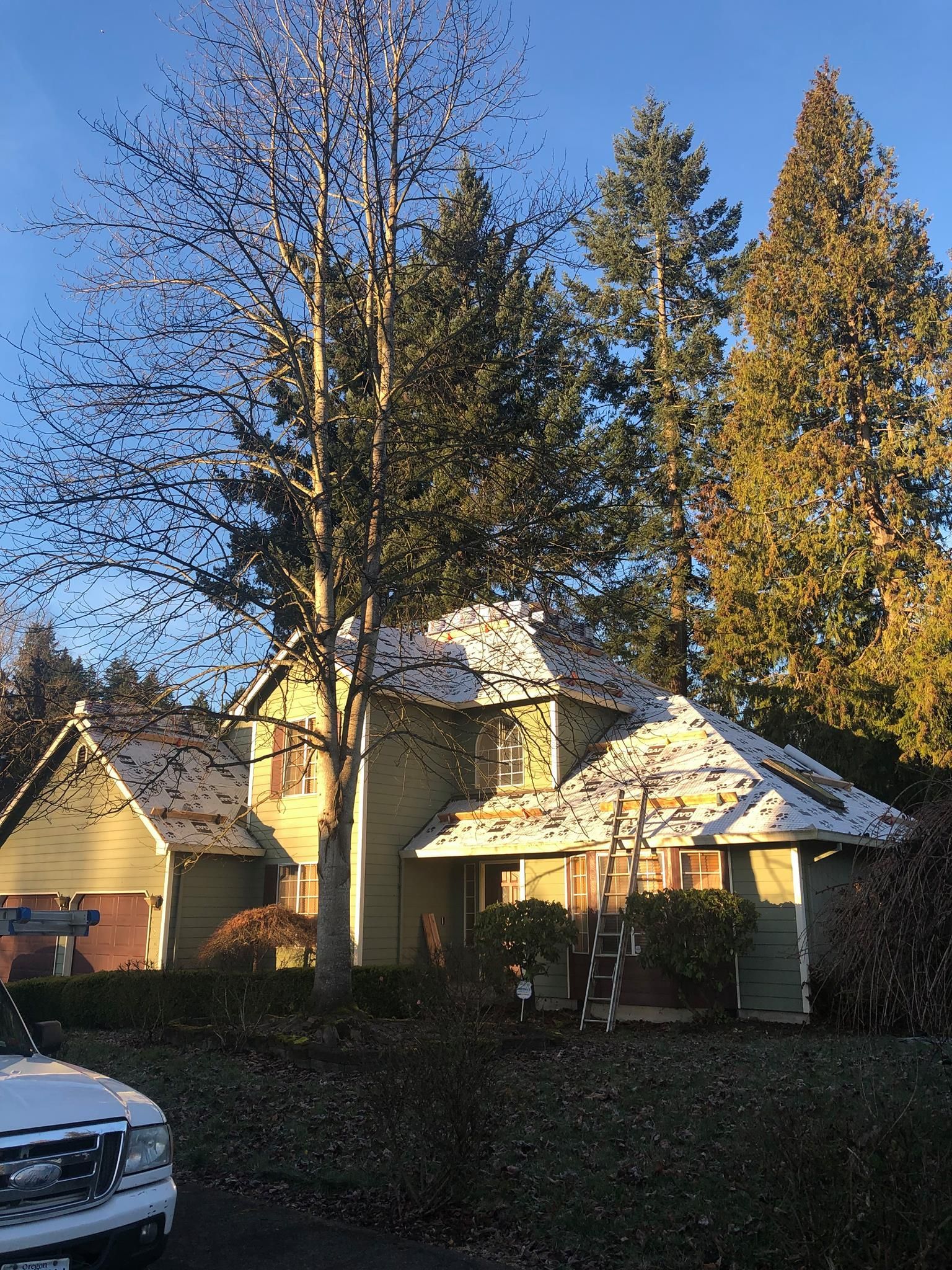A car is parked in front of a house with snow on the roof.