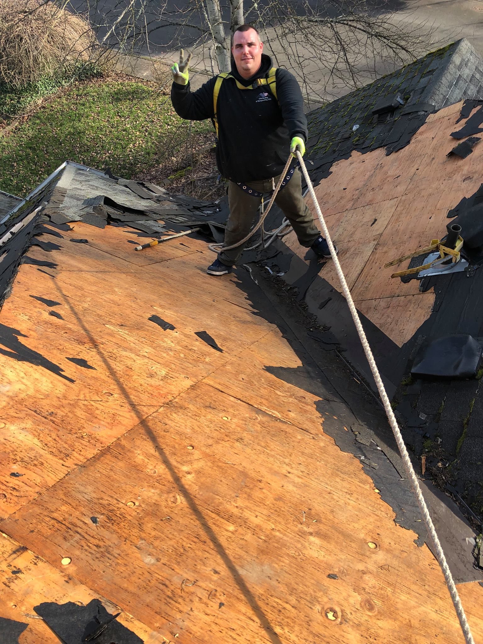 A man is standing on top of a roof holding a rope.