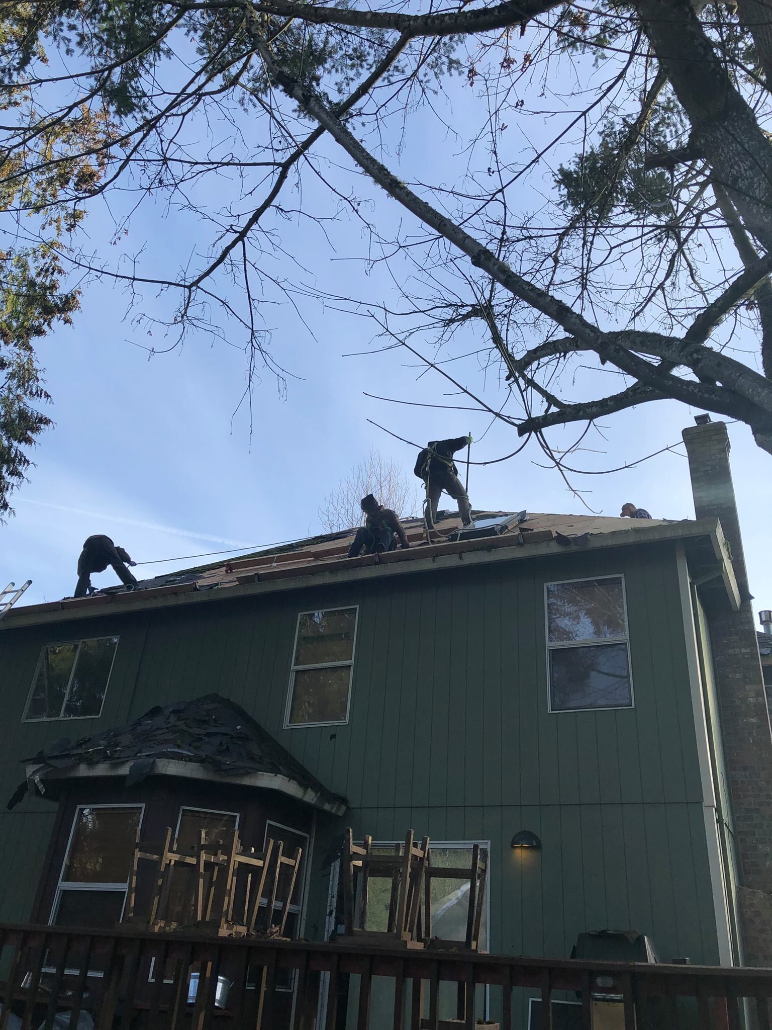 A group of men are working on the roof of a house.