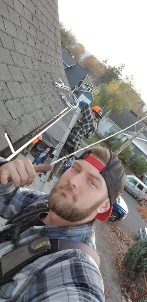 A man is standing on a roof holding a tool.