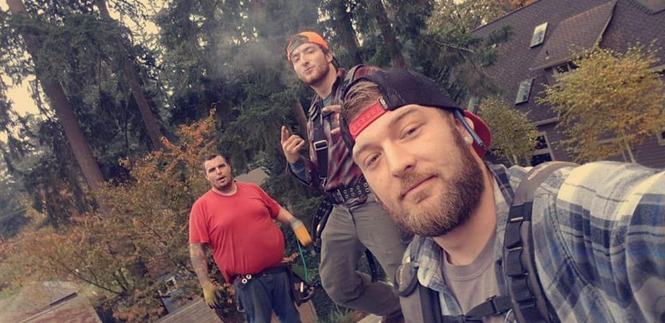 Three men are standing next to each other in front of a house taking a selfie.