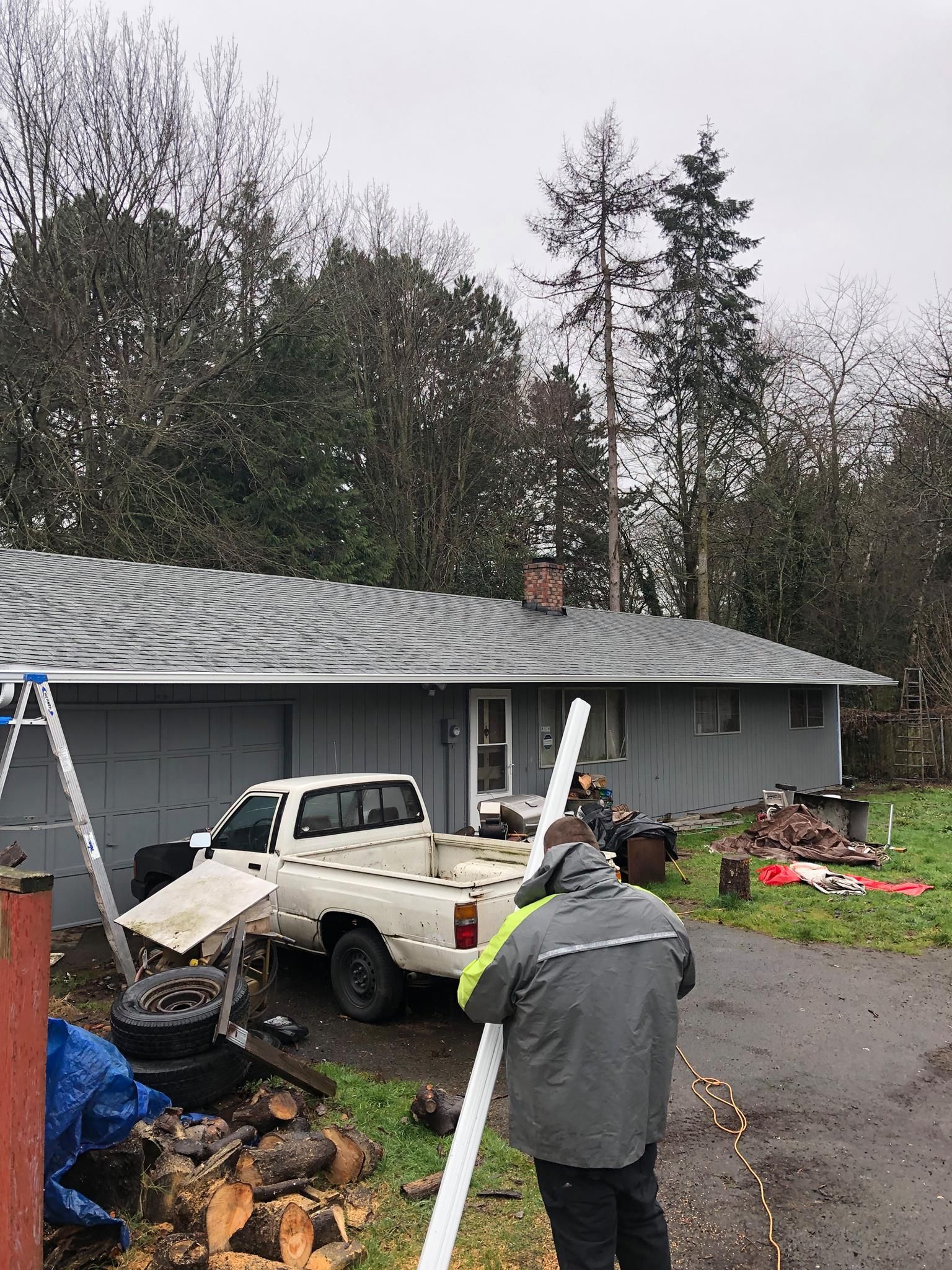 A man is standing in front of a house with a truck parked in front of it.