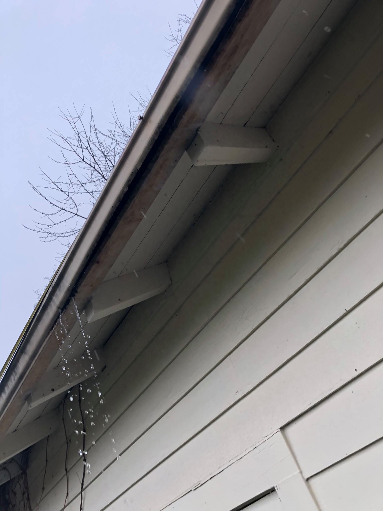 A white house with a gutter on the side of it.